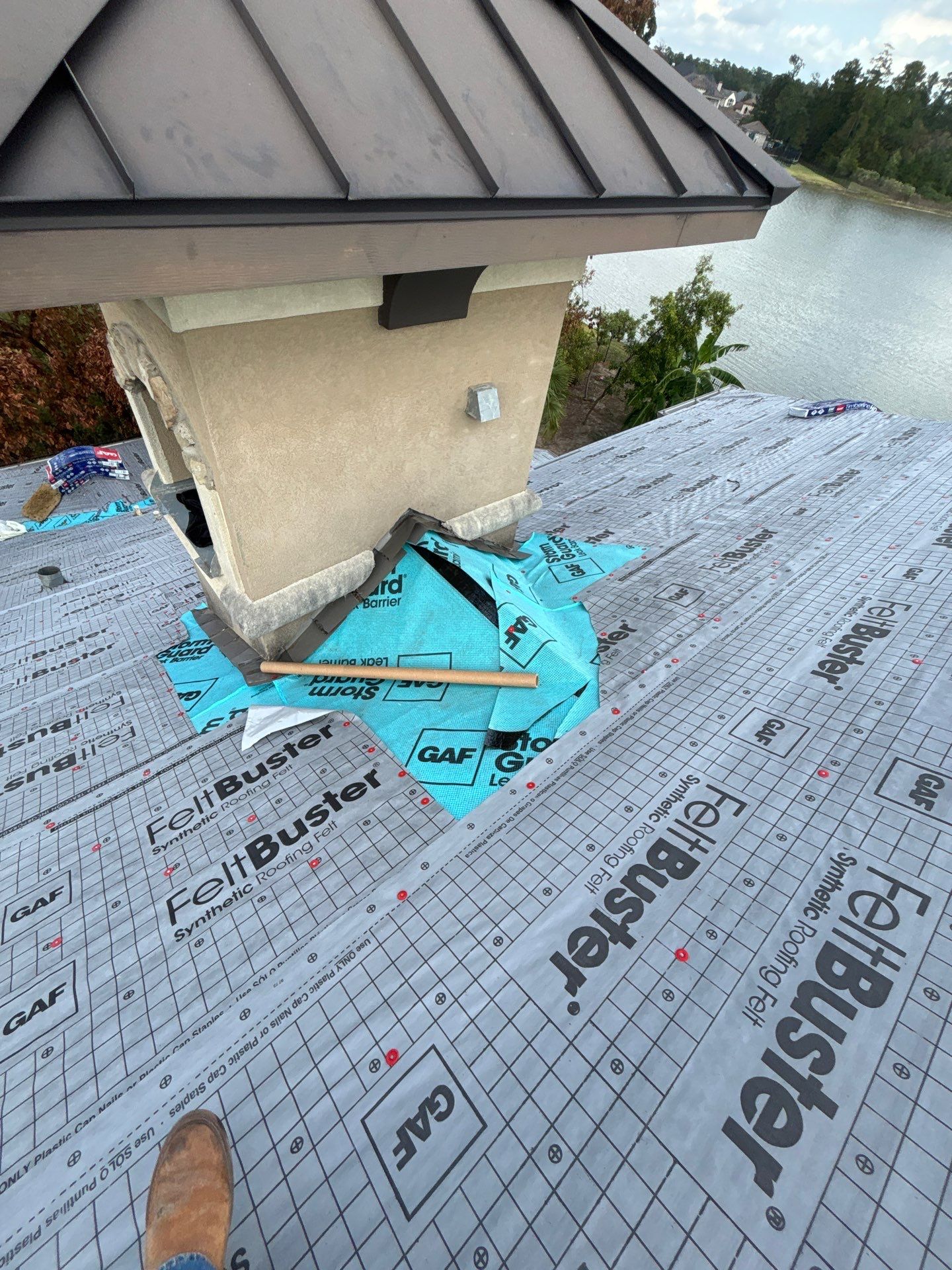 Chimney flashing rebuild on lakefront home in The Woodlands, TX — GAF StormGuard leak barrier and FeltBuster synthetic underlayment installed by Roof Repair Services